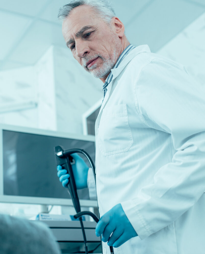 Calm male doctor with an endoscope in hands turning to his patient