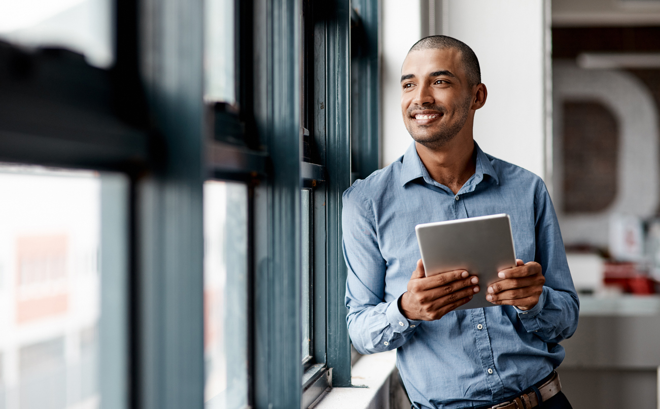 businessman using a digital tablet while standing at a window in an office
