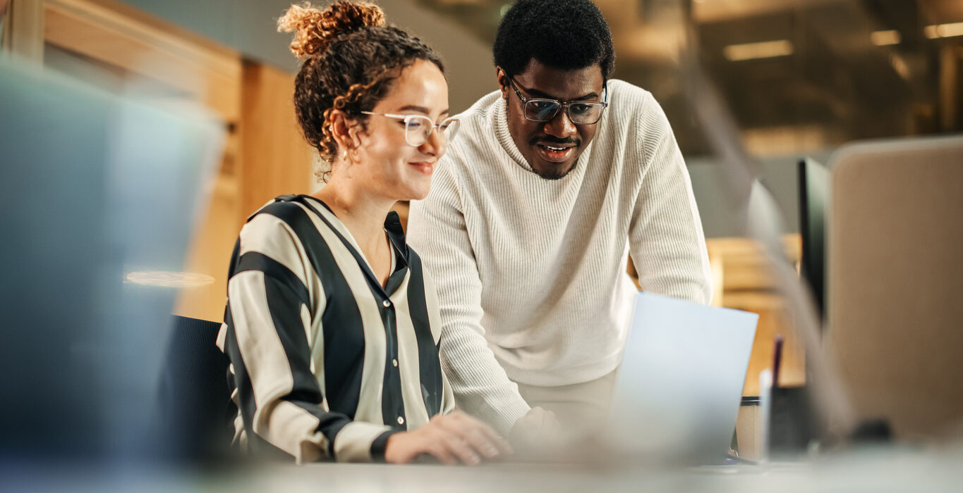 Colleagues Using Laptop to Discuss Work Project at Office