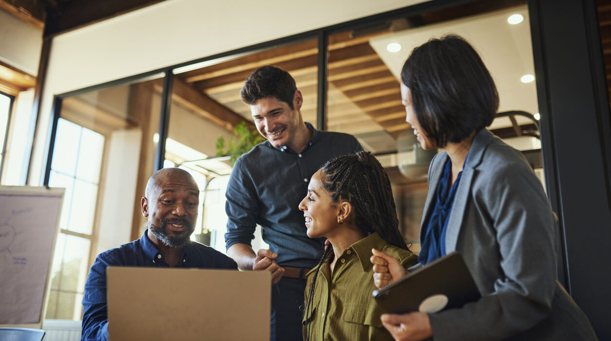 Project manager and teammates smiling cheerfully at team meeting in boardroom