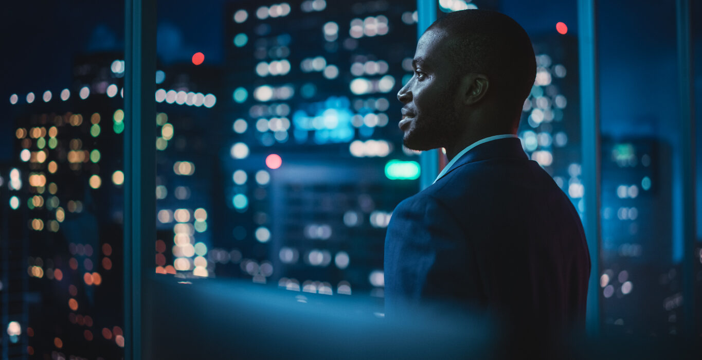 Successful Businessman Looking Out of the Window on Late Evening