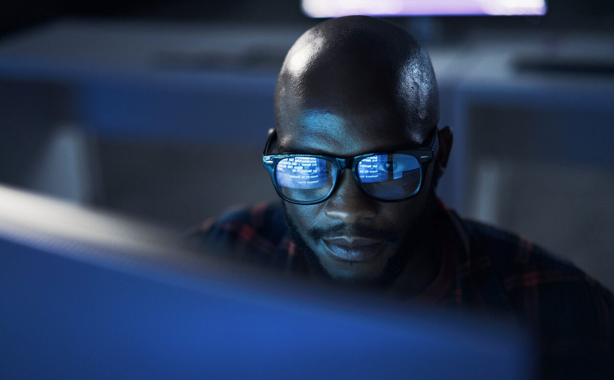 man and code reflection in his glasses as he looks at a screen