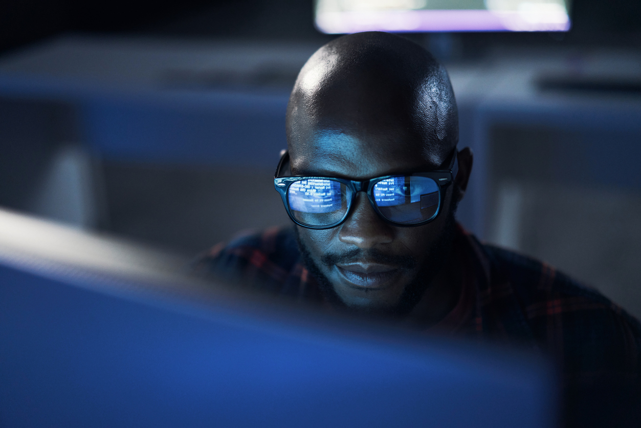 man and code reflection in his glasses as he looks at a screen