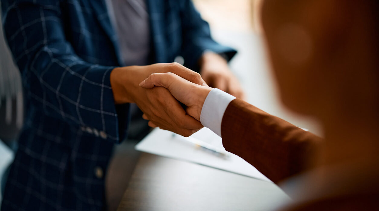 Close up of coworkers handshaking while greeting during business meeting in the office.