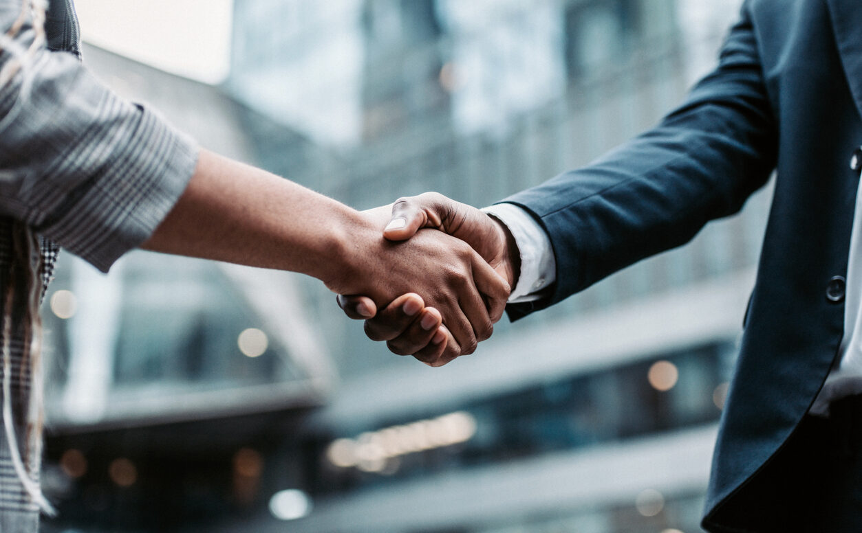 Two business persons shaking hands standing outside