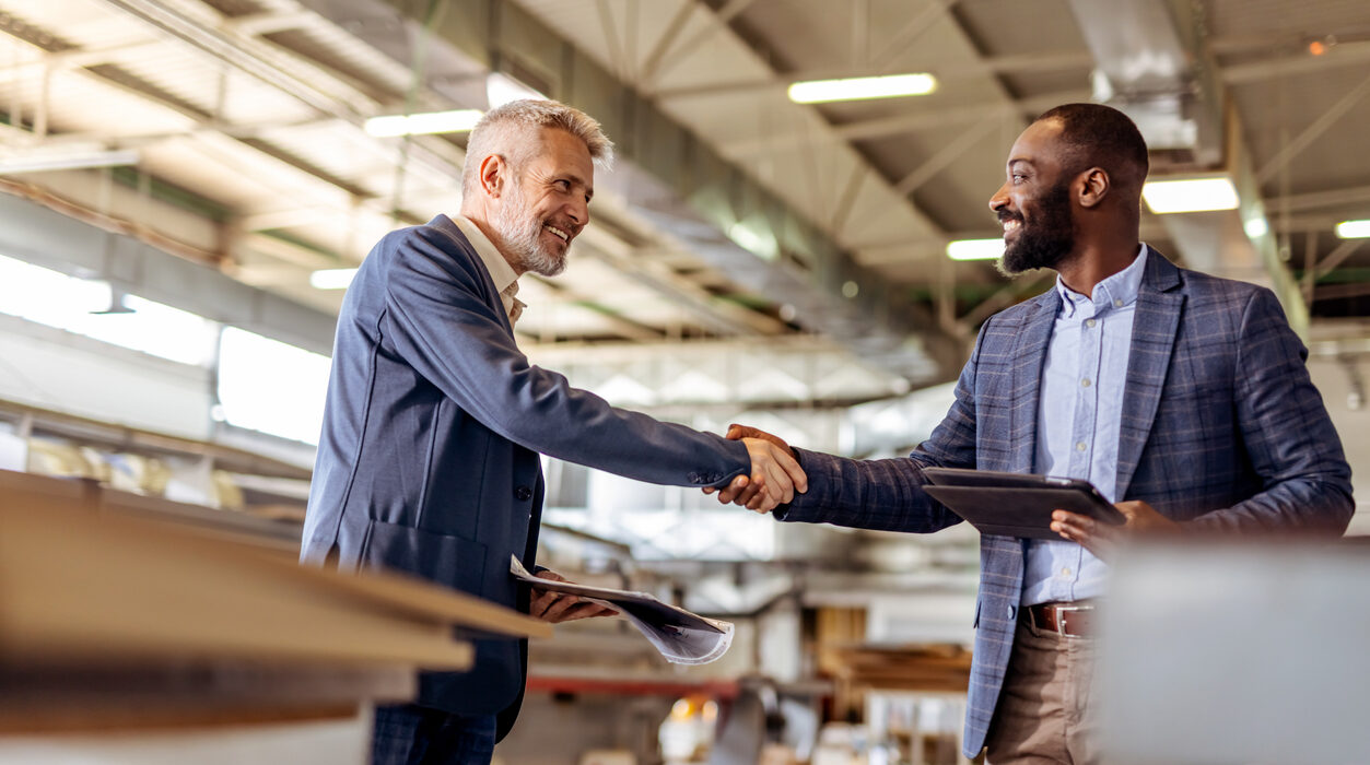 Two businessmen, one holding a tablet and the other documents