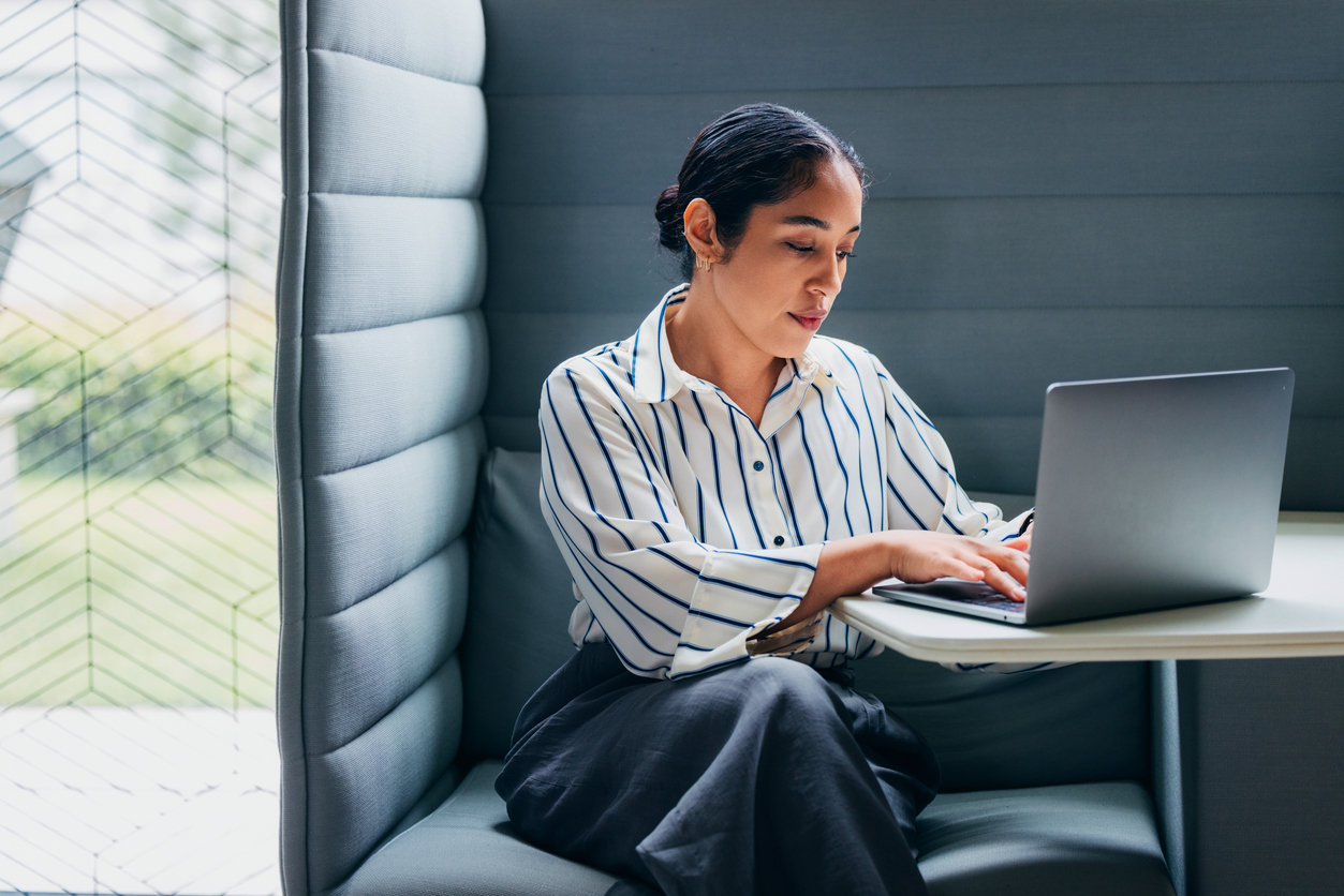 woman diligently using a laptop in a private, modern office workspace