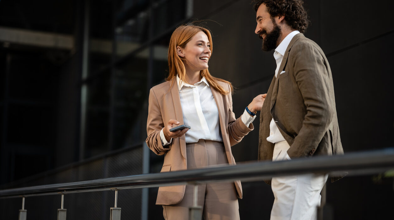 Two cheerful businesspeople are discussing work outside
