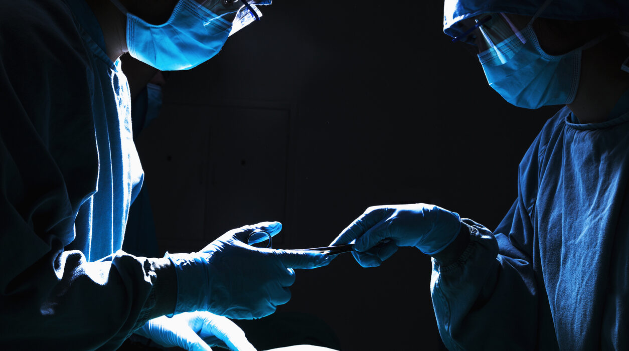 Two surgeons working and passing surgical equipment in the operating room
