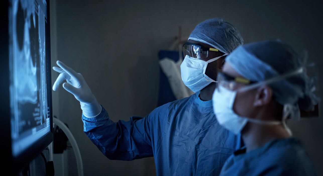 two surgeons analyzing a patient’s medical scans during surgery